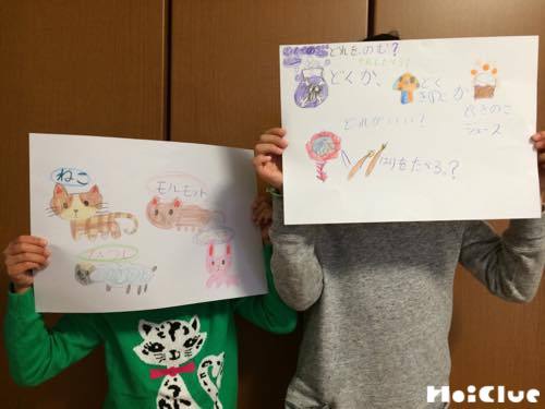 絵を描いた画用紙を掲げる子どもの写真