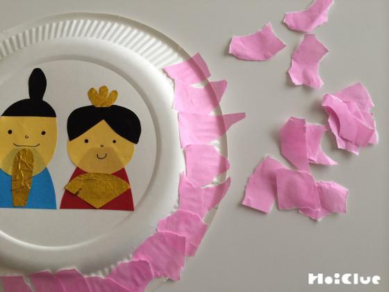 紙皿のふちにピンク色のちぎった折り紙を貼り付けている写真