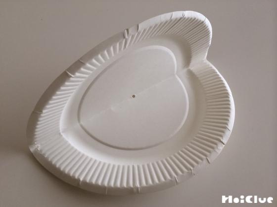 紙皿を半分に折り中心にきりで穴を開けた写真