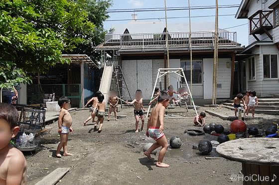 園庭でパンツ一丁になって水遊びをする子どもたちの様子
